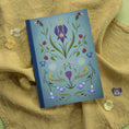 Load image into Gallery viewer, Notebook with floral design on a textured fabric background
