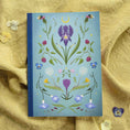 Cargar la imagen en la vista de la galería, Notebook with floral design on a textured yellow fabric background
